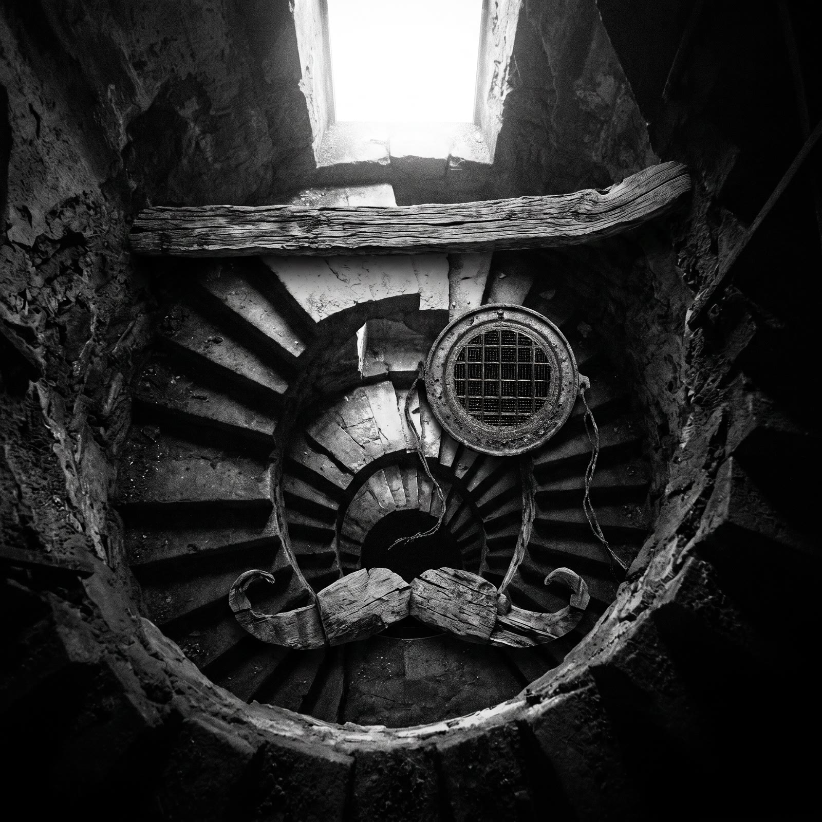 Pochette de Catabase : une cage d'escalier en ruine, vue de haut, dont les marches, une poutre et un hublot grillagé composent le visage du Baron.